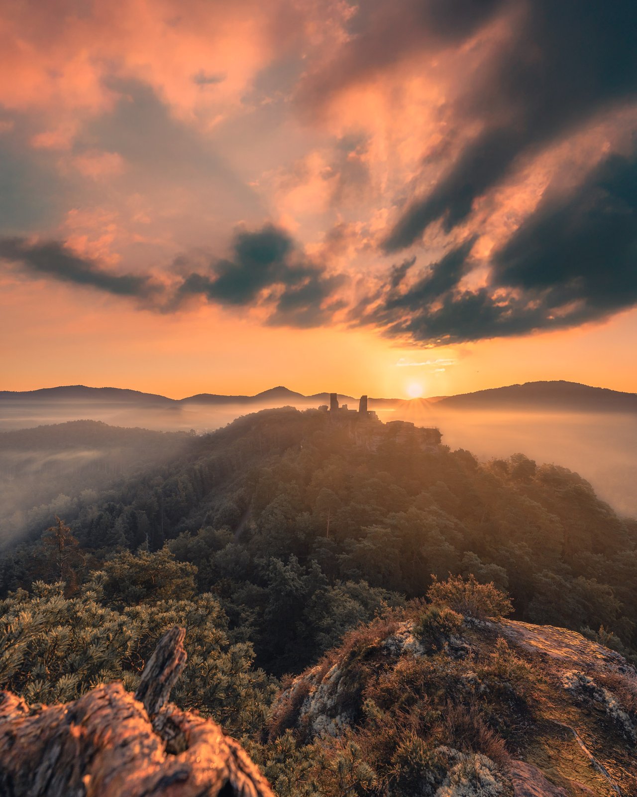 Burgruine im Morgennebel bei dramatischem Sonnenaufgang