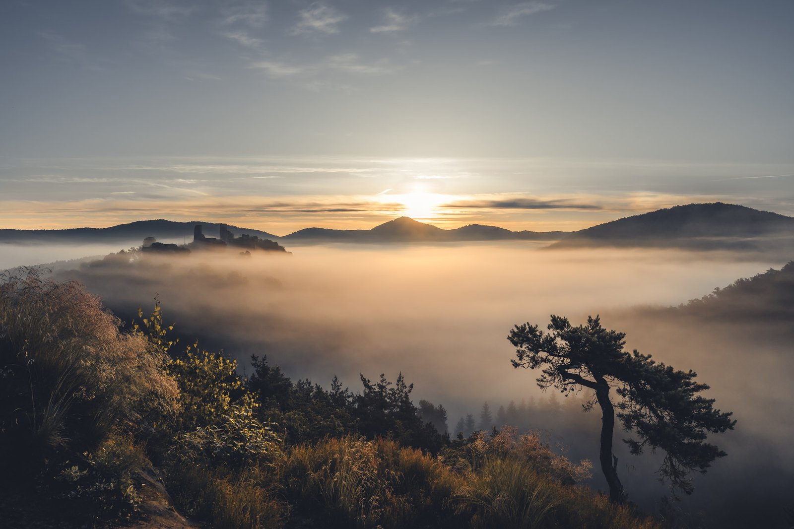 Burgruine ragt aus dem Nebelmeer im Morgenlicht