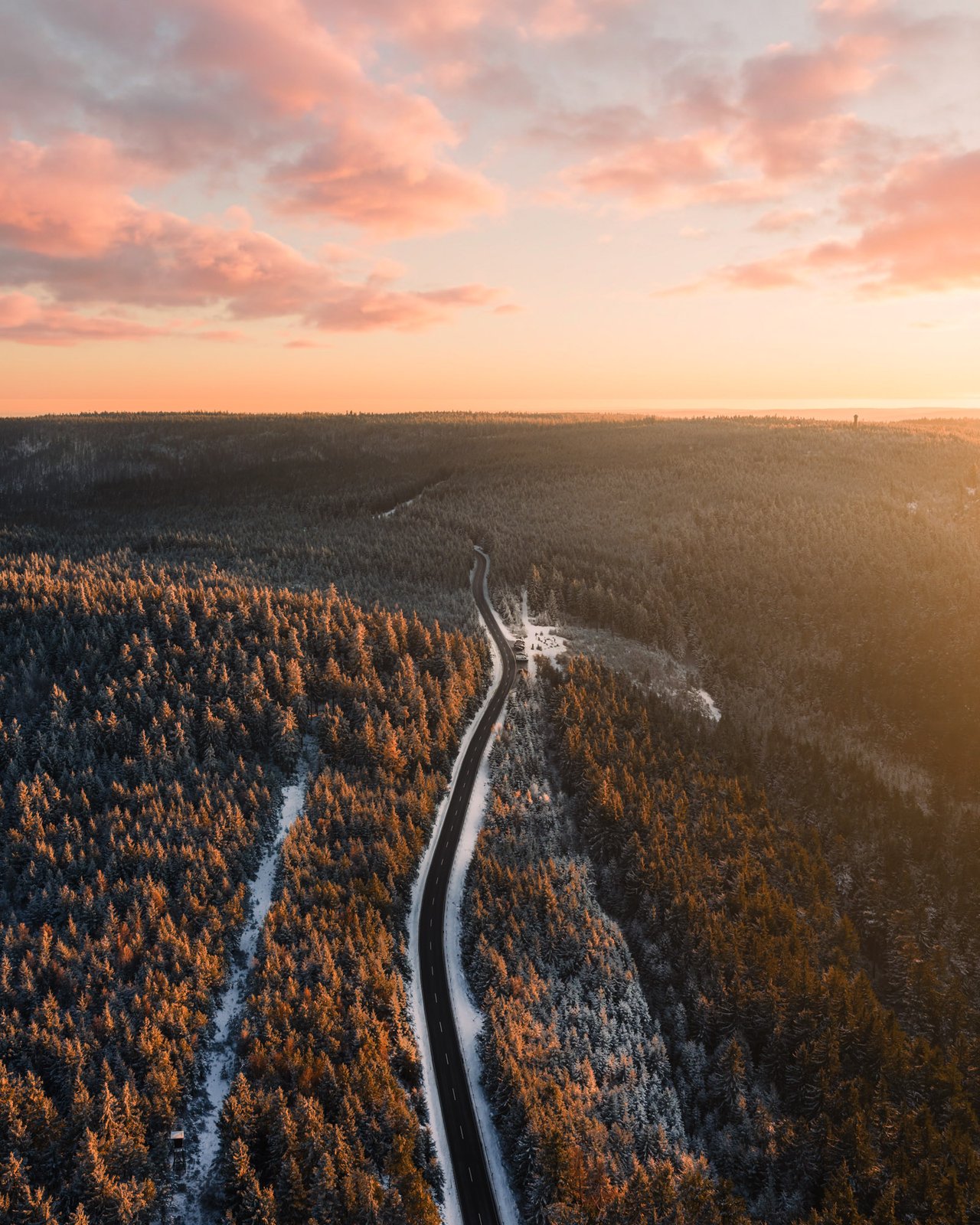 Schwarzwaldstraße durch verschneite Wälder bei rosafarbenem Morgenhimmel