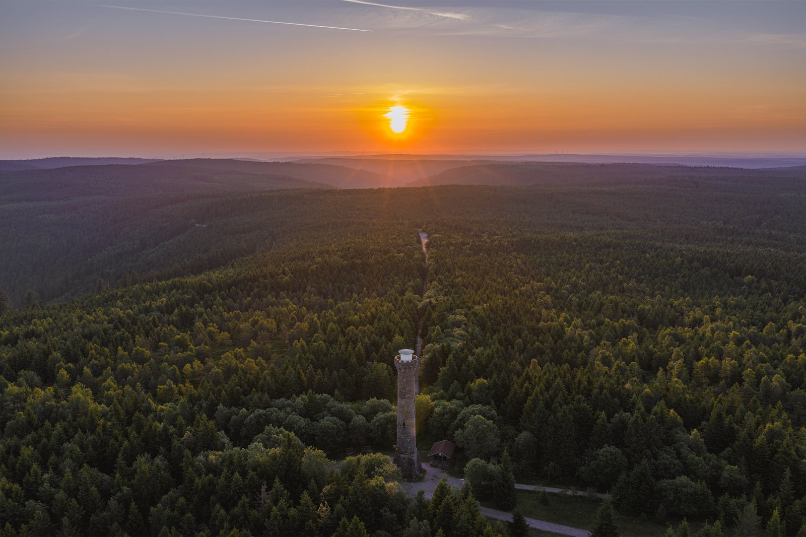 Drohnenaufnahme eines Aussichtsturms im endlosen Schwarzwald beim Sonnenuntergang