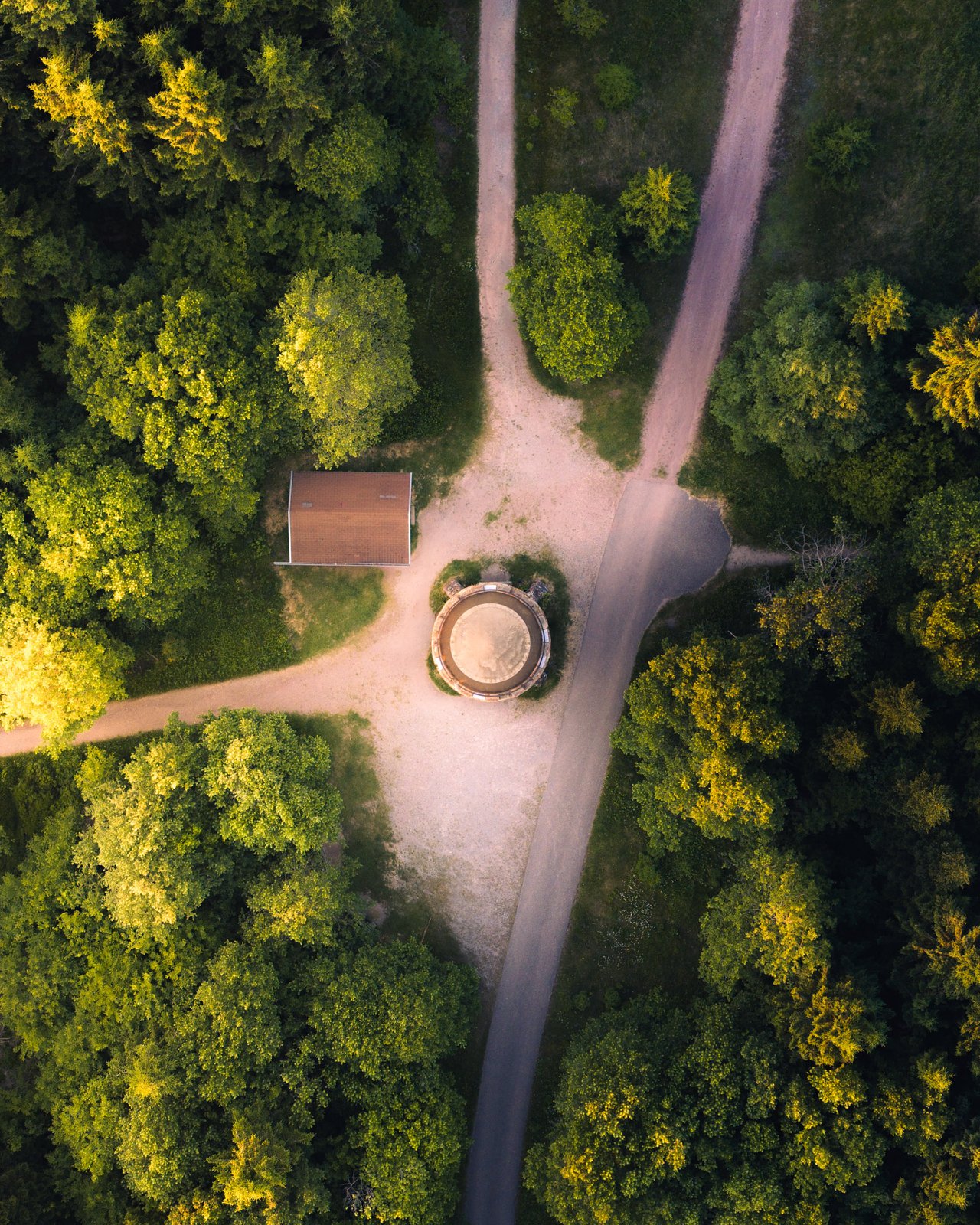 Drohnenaufnahme senkrecht nach unten auf Waldkreuzung mit altem Brunnen